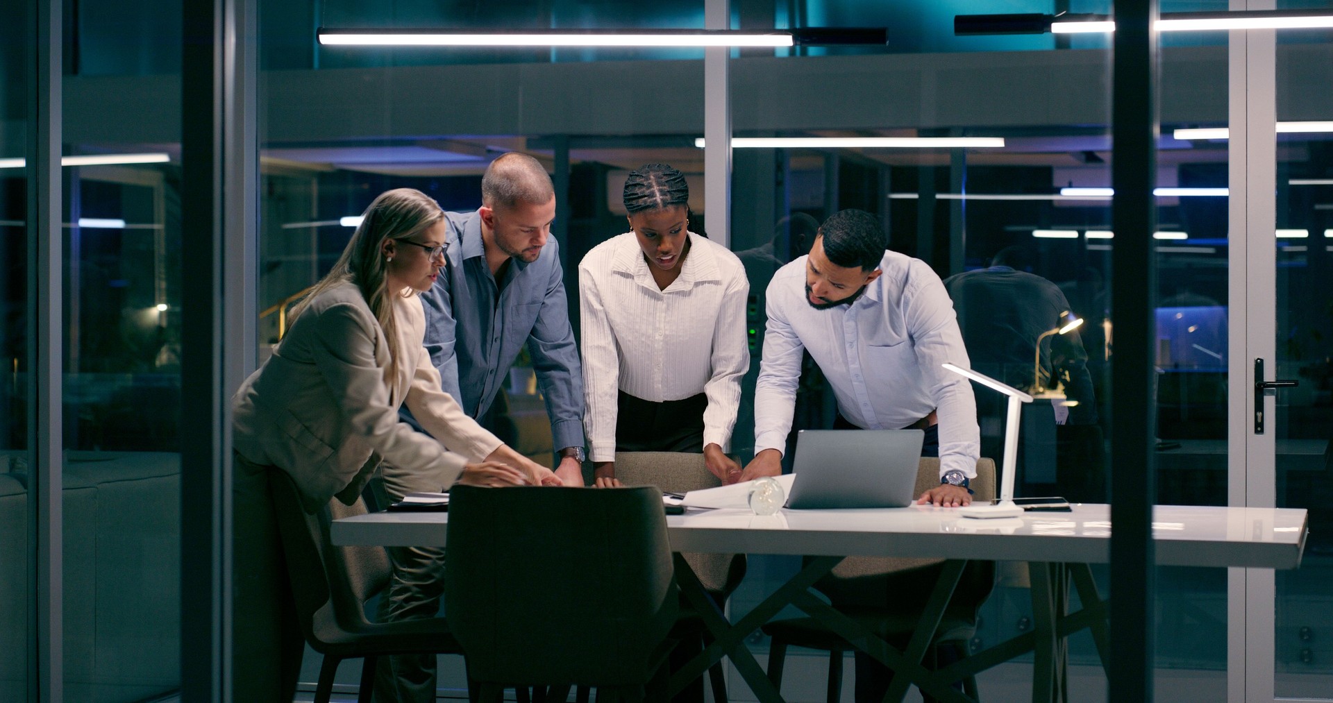 Meeting, planning and technology with business people in boardroom of office at night for project management. Administration, internet and teamwork with employee group in workplace for research